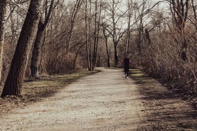 Alergător pe o alee acoperită cu frunze, într-o dimineață răcoroasă de toamnă