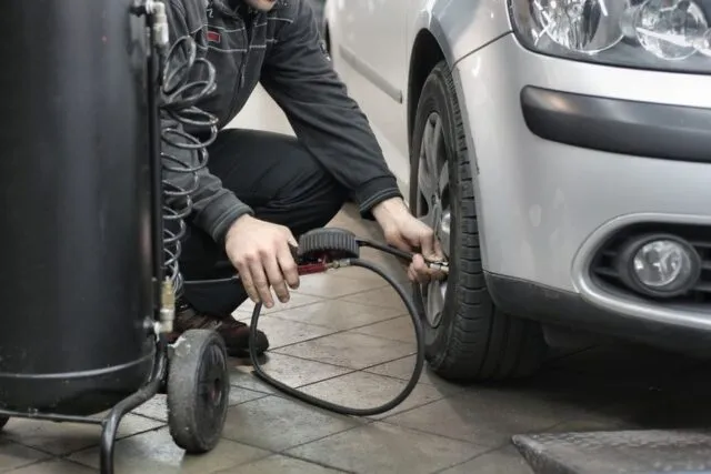 Un șofer verifică presiunea în anvelope înainte de un drum lung